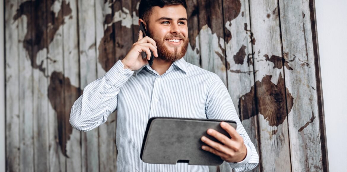 Handsome busy businessman talking on the phone and looking at important document on tablet.